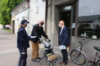 Wręczanie ulotki i maseczki osobie niepełnosprawnej przez policjanta i dyrektora PCPR