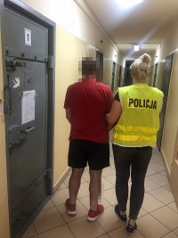 Policjantka pobiera zatrzymanego z pomieszczenia dla osób zatrzymnych