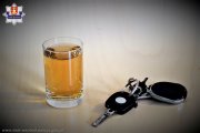 Szklanka z alkoholem stojąca na stole, a obok leżące kluczyki od samochodu