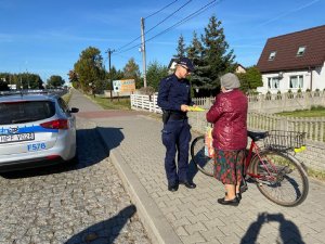 Policjant wręczający rowerzystce kamizelkę odblaskową