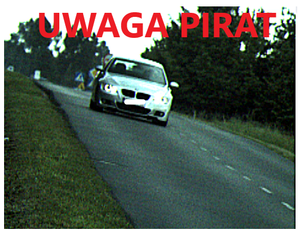 Białe BMW jedzie drogą, u góry zdjęcia napis: uwaga pirat
