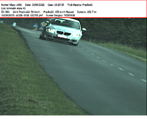 Białe BMW jedzie drogą i u góry zdjęcia zapis z wideorejestratora pokazujący prędkość 155 km/h