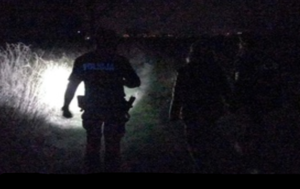 Na zdjęciu noc, policjant uczestniczący w poszukiwaniach  świeci latarką.