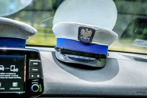 Na zdjęciu deska rozdzielcza radiowozu i czapka policyjna