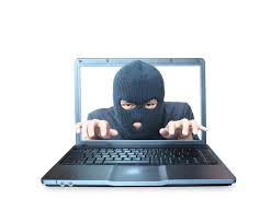 na zdjęciu osoba w czarnej masce przy klawiaturze, obrazująca oszusta w internecie