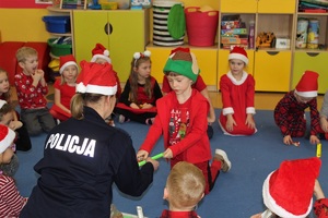 Policjantka rozdaje dzieciom opaski odblaskowe.