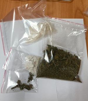 Różnego rodzaju narkotyki, spakowane w torebki strunowe, ułożone na stole.