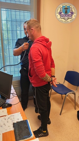 Policjant trzyma ustnik, mężczyzna dmucha do ustnika, by zbadać stan trzeźwości.