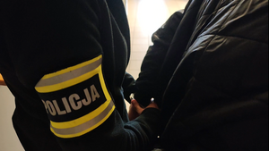 Policjant zakłada zatrzymanemu kajdanki.