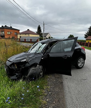 Uszkodzony samochód osobowy kolory czarnego, stojący przy przydrożnym rowie.