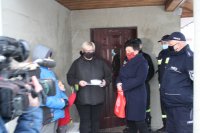 zdjęcie z wręczenia czujników czadu we wsi Kruszewiec  na zdjęciu cztery osoby od lewej dziecko kobieta  otrzymująca  czujnik,  soltys wsi Kruszewiec   oraz policjant
