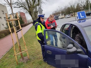 policjanci kontrolują z pracownkiem samochody do nauki jazdy