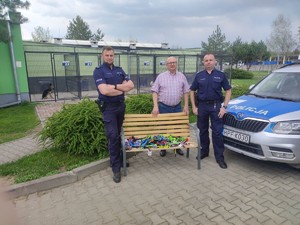 schronisko na łąwce leżą smycze i obroże, obok stoją polcijanci i pracownik schroniska, widać też piska w kojcu orz pozostałe psy w kojcach