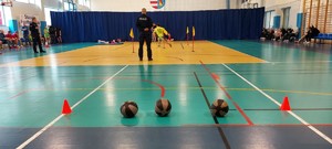 policjant w mundurze, na podłodze leżą trzy piłki lekarskie.