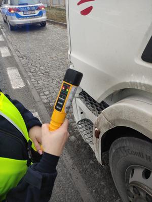 radiowóz policyjny, policjant trzyma w ręku urządzenie do badania trzeźwości, fragment kabiny samochodu.