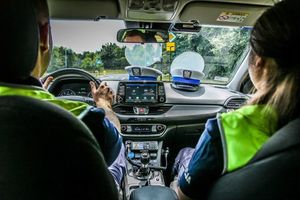 policjanci siedzą w radiowozie, na kokpicie leżą czapki policyjne.