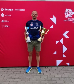 mężczyzna trzyma dwa puchary.