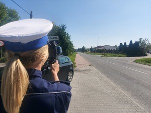 policjantka w białej czapce, samochód w kolorze czarnym, droga.