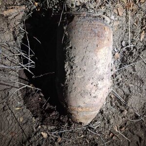 przedmiot w kształcie pocisku, ubrudzony w ziemi leży na trawie.