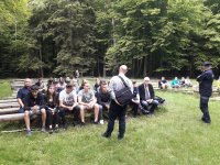 młodzież słuchająca wykłądu nauczyciela historii o żołnierzach walczących podczas II wojny światowej w WYkusie  w tle postać komendanta  policji w mundurze