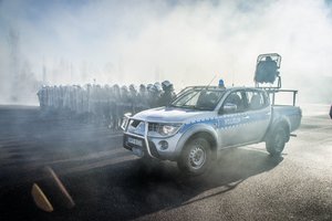 Radiowóz marki „Mitsubishi” z urządzeniem nagłaśniającym LRAD stoi obok stojących w tyralierze policjantów z Oddziału Prewencji Policji w Łodzi.