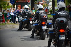 obraz przedstawia kolumnę 3 motocyklów policyjnych z siedzącymi na nich policjantami w kaskach. Widok od tyłu