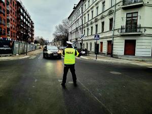 Policjant wydziału ruchu drogowego kierujący ruchem na skrzyżowaniu.